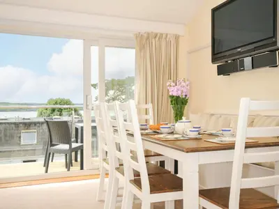 a dining room with a table and a large window at 9 Slipway Cottages in Wadebridge