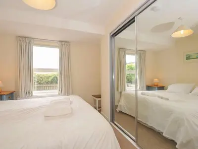 a bedroom with two beds and a large window at 9 Slipway Cottages in Wadebridge