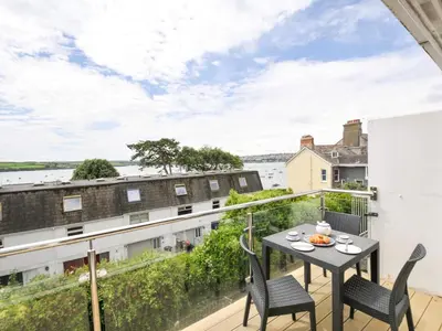 a balcony with a table and chairs and a view of the water at 9 Slipway Cottages in Wadebridge