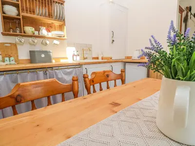 a kitchen with a wooden table and a vase of flowers at Lavender Cottage in Helston