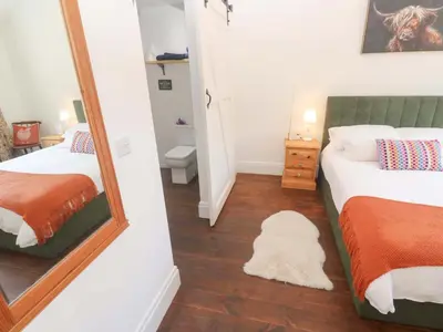 a bedroom with two beds and a mirror at Lavender Cottage in Helston