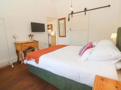 a bedroom with a large white bed and a desk at Lavender Cottage in Helston