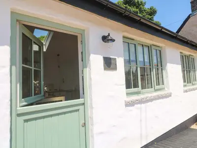 a house with a green door and windows at Lavender Cottage in Helston