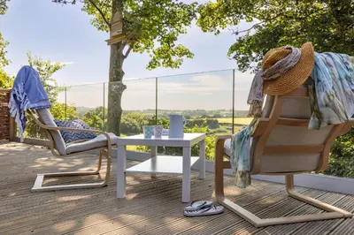 a patio with two chairs and a table on a deck at Owl Lodge in Liskeard