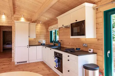 a kitchen with white cabinets in a wooden cabin at Owl Lodge in Liskeard