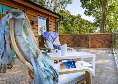 a patio with a table and chairs on a deck at Owl Lodge in Liskeard