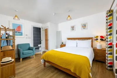 a bedroom with a bed and a blue chair at Blue Mist Studio in St Ives