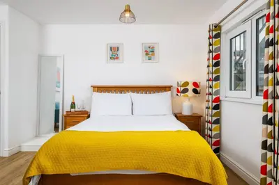 a bedroom with a bed with a yellow blanket at Blue Mist Studio in St Ives