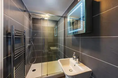 a bathroom with a sink and a shower and a mirror at Blue Mist Studio in St Ives