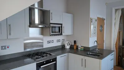 a kitchen with white cabinets and stainless steel appliances at Tate Five Penthouse apartment with panoramic views of St Ives in St Ives