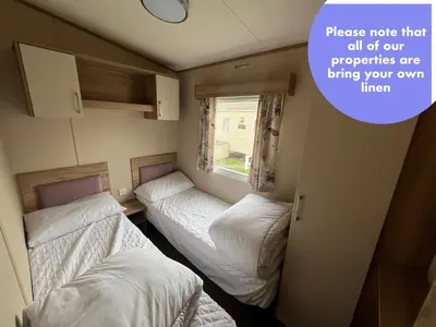 a small room with two beds and a window at Cornish Caravan Escapes in Porth