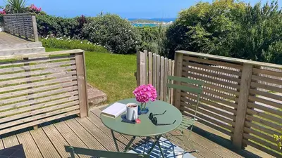 a table with a book and flowers on a deck at Sea view Studio by Fistral Beach in Newquay