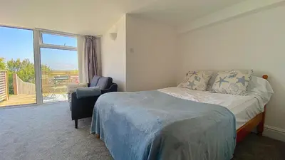 a bedroom with a bed and a chair and a window at Sea view Studio by Fistral Beach in Newquay