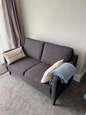 a gray couch with pillows in a living room at Sea view Studio by Fistral Beach in Newquay