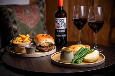 a table with two plates of food and a glass of wine at Basset Arms, Portreath, Cornwall in Portreath