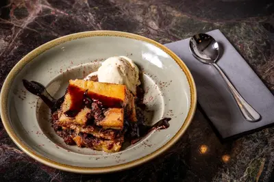 a plate with a piece of cake with a scoop of ice cream at Basset Arms, Portreath, Cornwall in Portreath