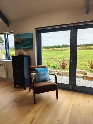 a living room with a chair and a large sliding glass door at Ocean Heart Studio- Luxury, Rural Retreat in Wendron