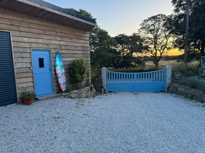 a surfboard next to a house with a blue door at Ocean Heart Studio- Luxury, Rural Retreat in Wendron