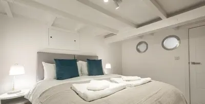 a white bedroom with a large bed with two mirrors at VITAMYN SEA, 4 bedroom house, Sleeps 8, 6 beds, Sea views, 5 min walk to harbour and beaches in St Ives