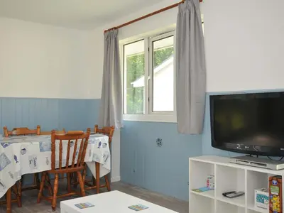 a living room with a television and a table with chairs at 4 Rosecraddoc Lodge Holiday Bungalows in Liskeard