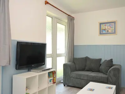 a living room with a couch and a television at 4 Rosecraddoc Lodge Holiday Bungalows in Liskeard