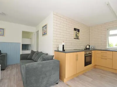a living room with a couch and a kitchen at 4 Rosecraddoc Lodge Holiday Bungalows in Liskeard