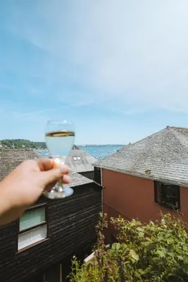 a person holding a glass of wine on a balcony at Merthen House in Falmouth