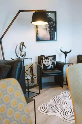 a living room with black chairs and a lamp at Merthen House in Falmouth
