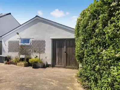 a house with a large bush next to a garage at Gwennel Nook in St. Agnes