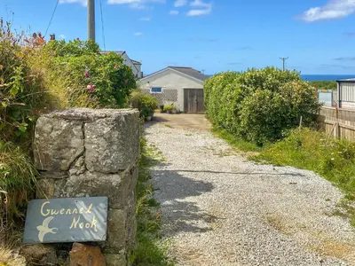 a gravel road with a sign on a rock at Gwennel Nook in St. Agnes