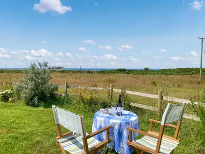 two chairs and a table with a bottle of wine at Gwennel Nook in St. Agnes