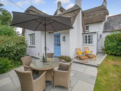 a patio with a table and chairs and an umbrella at Penda in Porthscatho
