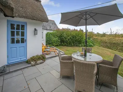 a table and chairs with an umbrella on a patio at Penda in Porthscatho