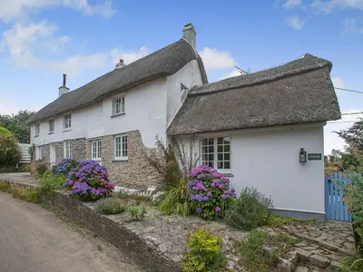 a white house with flowers on the side of a road at Penda in Porthscatho