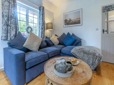 a living room with a blue couch and a table at Penda in Porthscatho