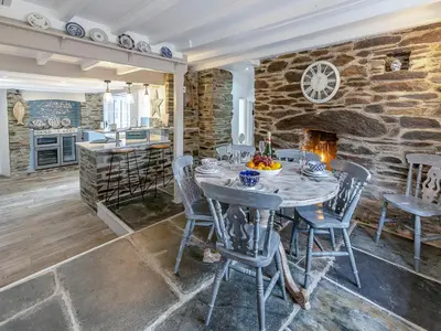 a dining room with a table and a stone wall at Penda in Porthscatho