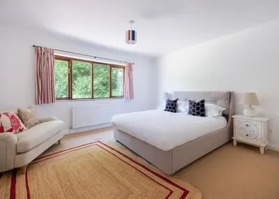 a white bedroom with a bed and a couch at Idle Rock in Polzeath