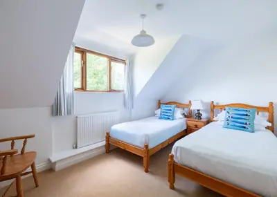 two beds in a room with white walls and windows at Idle Rock in Polzeath