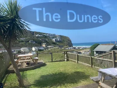 a sign that reads the dunes with a picnic table and a tree at 'The Dunes', Porthtowan in Porthtowan