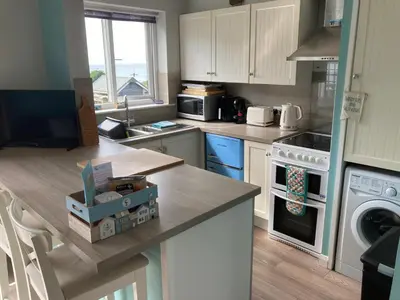 a kitchen with white cabinets and a stove top oven at 'The Dunes', Porthtowan in Porthtowan