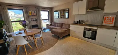 a kitchen and living room with a table and a couch at Shorebreak Apartment 2 in Newquay