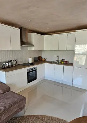 a kitchen with white cabinets and a sink at Shorebreak Apartment 2 in Newquay