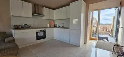 a kitchen with white cabinets and a large window at Shorebreak Apartment 2 in Newquay