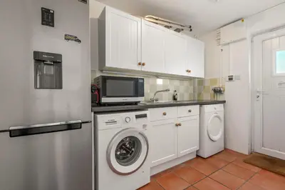 a kitchen with a washing machine and a microwave at Gully at Highcliffe in Polzeath