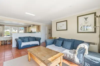 a living room with a blue couch and a table at Gully at Highcliffe in Polzeath