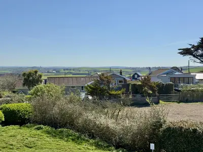 a group of houses in a field with bushes at Gully at Highcliffe in Polzeath