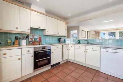 a kitchen with white cabinets and a tile floor at Gully at Highcliffe in Polzeath