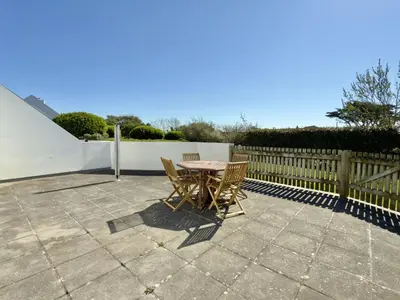 a table and chairs on a patio with a fence at Gully at Highcliffe in Polzeath