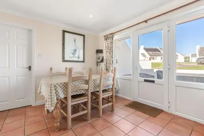 a dining room with a table and chairs and a window at Gully at Highcliffe in Polzeath