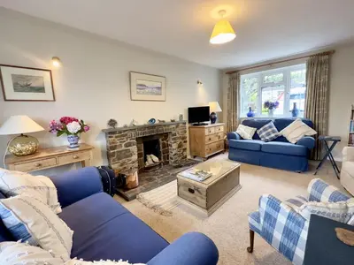 a living room with blue couches and a fireplace at Choughs in Saint Minver